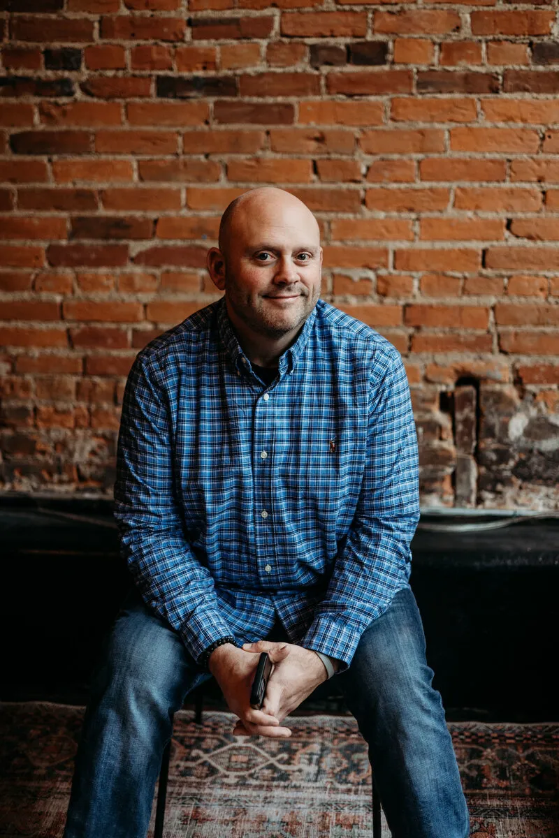 Jeremy Kean, founder of Kean on Biz, sitting in front of a brick wall